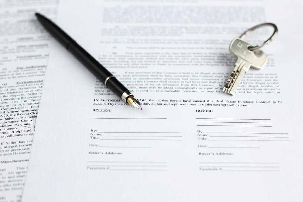 Legal document for sale of real estate, with a gold-nibbed fountain pen and house keys