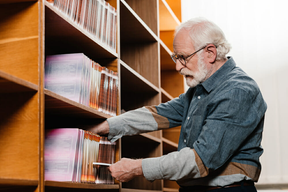 Side view of grey hair librarian searching for book